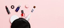 Top View Of Set Of Make Up And Skin Care Products Spilling Out Of Cosmetics Bag On Pink Background. Beauty Concept