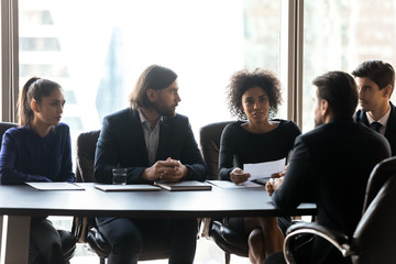 Wall Mural - Confident African American businesswoman hr manager asking questions to candidate on job interview, holding resume cv, four recruiters sitting at table in boardroom, looking at job applicant