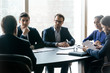 © fizkes - Serious confident businesspeople listening to mentor leader at meeting in boardroom, sitting at table at briefing, business partners colleagues discussing project strategy, contract terms