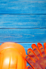 Orange hard hat and gloves on wooden vintage blue boards