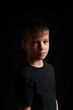 young boy in a black t-shirt on a black background