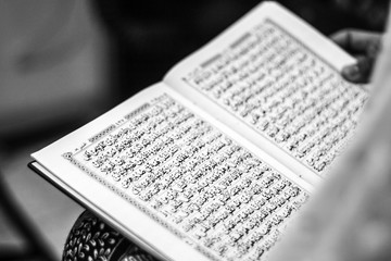 Reading Quran in hand - holy book of Muslims, black and white photo