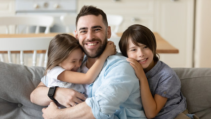 Wall Mural - Happy small brother sister cuddling smiling dad, looking at camera. Head shot portrait joyful little children missed daddy, celebrating Father s Day, spending free weekend leisure time together.