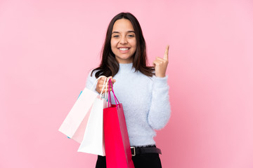 Wall Mural - Young woman with shopping bag over isolated pink background pointing up a great idea