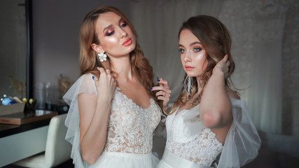 Wall Mural - Two young models posing in front of the photographer in a wedding dress.