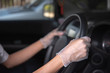 © Onkamon - The arm of a man wearing gloves to hold a steering wheel for prevent covid-19 virus infection.