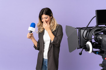 Reporter teenager girl holding a microphone and reporting news isolated on purple background smiling a lot