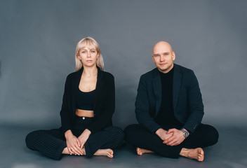 Young beautiful couple is sitting on a floor in pose lotus.