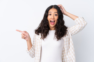 Canvas Print - Mixed race woman over isolated white background surprised and pointing finger to the side