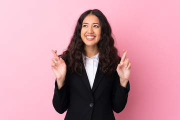 Wall Mural - Mixed race business woman over isolated pink background with fingers crossing