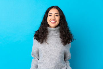 Wall Mural - Spanish Chinese woman over isolated blue background laughing