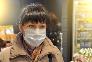 Young woman wearing disposable medical mask shopping in supermarket during coronavirus pneumonia outbreak. Protection and prevent measures while epidemic time.