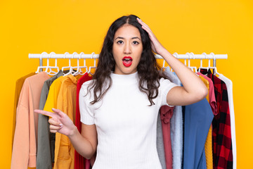 Wall Mural - Mixed race woman in a clothing store surprised and pointing finger to the side