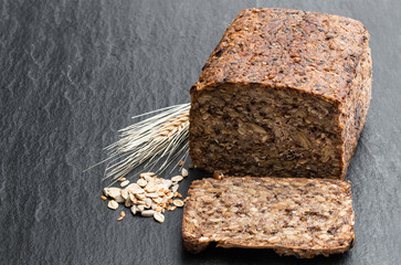 Super seed vegan loaf free from wheat and yeast on black stone background