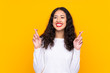 © luismolinero - Mixed race woman over isolated yellow background with fingers crossing