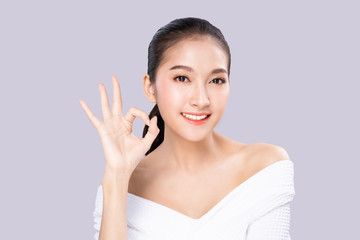 Beautiful Young Asian woman with  fresh white skin with smile face show okay pose. Girl smile with beautiful white teeth and good arranged teeth. Facial treatment, cosmetology, make up, braces dental.