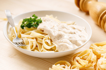 Italian pasta fettuccine in creamy sauce on wooden table