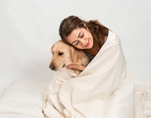 Wall Mural - Female woman girl hugging with her labrador retriever dog wrapped n a white blanket. Romantic relationship human and dog concept