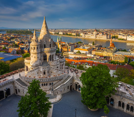 Budapest, Hungary - Aerial view of the famous Fisherman's Bastion at sunset with Parliament building at background. Warm sunlight, blue sky, no people on a sunny spring afternoon