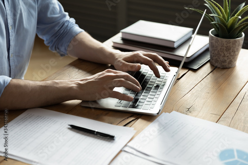 Cuadros en Lienzo Close up businessman using laptop, typing on keyboard, sitting at wooden desk wi