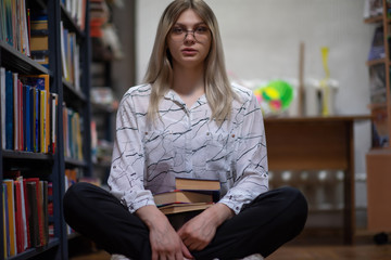 Young blonde girl with glasses in the library. Photographed close-up.