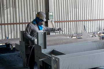 Wall Mural - The painter is working to painting the steel structure with spray gun at industrial factory.