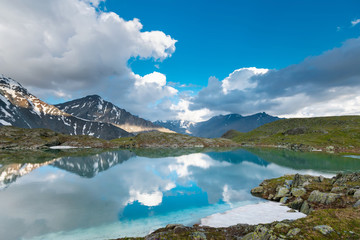 Canvas Print - Green lake between mountains in cloudy day