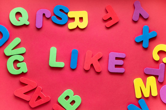 Word LIKE From Plastic Magnetic Letters On Red Background