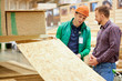 © alfa27 - warehouse worker show the best variant of wooden board in their market, customer looking for building material