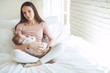 © nuzza11 - Beautiful woman breastfeeding her baby in a cozy house on the bed.