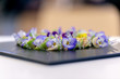 Des petits-fours fleuris violet pour une conférence sur un plateau en inox