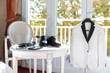 Table à thé, avec les accessoires, chaussures, montre du marié et sa veste devant un fenetre