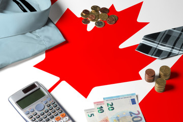 Canada flag on minimal money concept table. Coins and financial objects on flag surface. National economy theme.