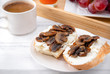 2 sandwiches with  cheese and mushrooms on a plate, a Cup of black coffee on a white wooden