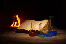 Medieval Alchemy And Pharmacy Concept With Old Book And Bottles With Medicine. Text In The Book Is Not Recognizible.