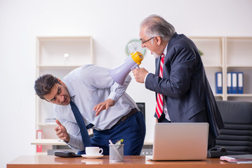 Old boss and young male employee in the office