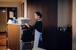 A hotel maid in a uniform cleaning the rooms in a hotel