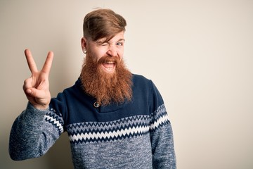 Poster - Handsome Irish redhead man with beard wearing winter sweater over isolated background smiling with happy face winking at the camera doing victory sign. Number two.