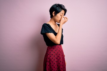 Poster - Young beautiful asian girl wearing casual dress standing over isolated pink background tired rubbing nose and eyes feeling fatigue and headache. Stress and frustration concept.