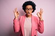 © Krakenimages.com - Young beautiful African American afro businesswoman with curly hair wearing pink jacket looking surprised and shocked doing ok approval symbol with fingers. Crazy expression