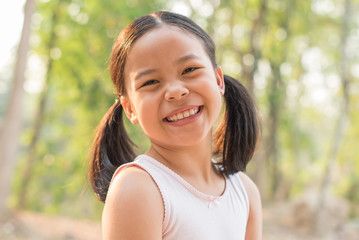 sweet little girl outdoors in the wind. portrait of attractive little student girl with beautiful. happy smiling child looking at camera - close-up, outdoors. jolly nature childhood leisure concept.