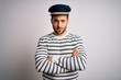 © Krakenimages.com - Young handsome sailor man with beard wearing navy striped uniform and captain hat skeptic and nervous, disapproving expression on face with crossed arms. Negative person.