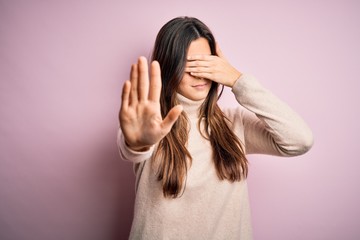 Wall Mural - Young beautiful girl wearing casual turtleneck sweater standing over isolated pink background covering eyes with hands and doing stop gesture with sad and fear expression. Embarrassed and negative