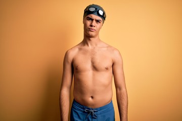 Poster - Young handsome man shirtless wearing swimsuit and swim cap over isolated yellow background depressed and worry for distress, crying angry and afraid. Sad expression.