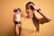 © Krakenimages.com - Young beautiful brunette woman holding gym bottle shaker with protein beverage for diet stressed with hand on head, shocked with shame and surprise face, angry and frustrated. Fear and upset