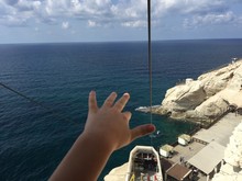 Cropped Hand Of Kid Against Sea At Rosh Hanikra Grottoes