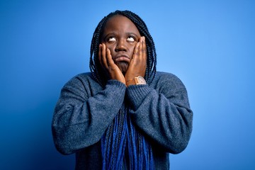 Canvas Print - African american plus size woman with braids wearing casual sweater over blue background Tired hands covering face, depression and sadness, upset and irritated for problem