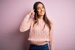 © Krakenimages.com - Young beautiful brunette woman wearing casual sweater over isolated pink background Smiling pointing to head with one finger, great idea or thought, good memory