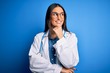 © Krakenimages.com - Young beautiful doctor woman wearing stethoscope and glasses over blue background with hand on chin thinking about question, pensive expression. Smiling with thoughtful face. Doubt concept.