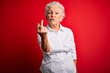 Senior beautiful woman wearing elegant shirt standing over isolated red background Showing middle finger, impolite and rude fuck off expression